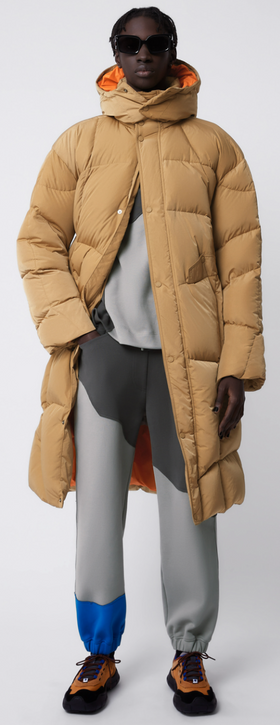A man wearing a puffy beige Ader-error jacket with grey pants
