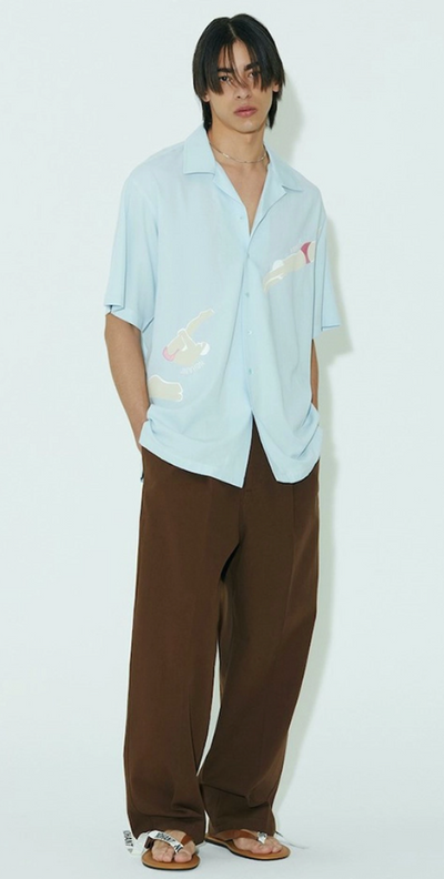 A man wearing a baggy Nohant button up and brown loose fitting pants