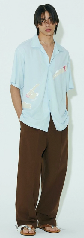 A man wearing a baggy Nohant button up and brown loose fitting pants