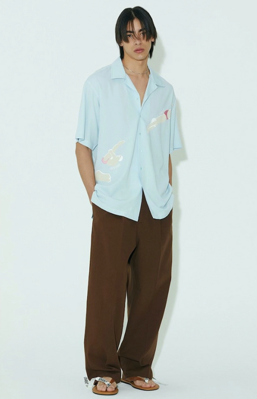 A man wearing a baggy Nohant button up and brown loose fitting pants
