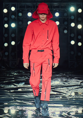 A man wearing an all red 99%IS technical outfit featuring an oversize hat