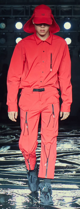 A man wearing an all red 99%IS technical outfit featuring an oversize hat