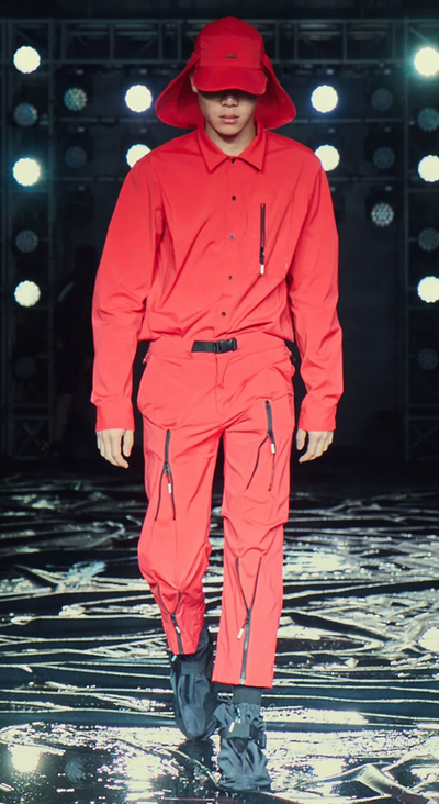 A man wearing an all red 99%IS technical outfit featuring an oversize hat