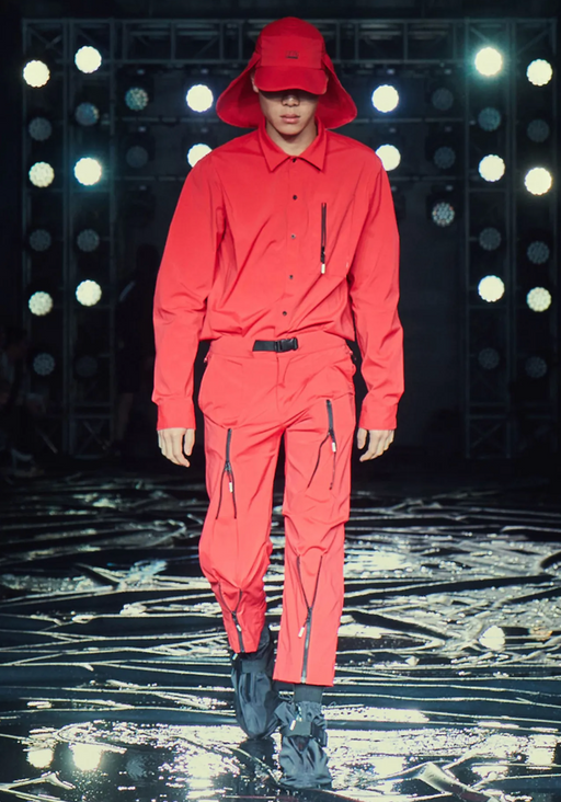 A man wearing an all red 99%IS technical outfit featuring an oversize hat
