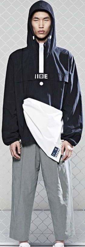 A man wearing a blue hoodie by IISE Seoul with grey slacks