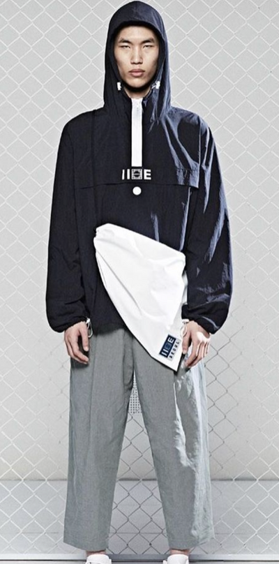 A man wearing a blue hoodie by IISE Seoul with grey slacks