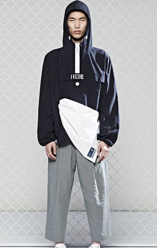 A man wearing a blue hoodie by IISE Seoul with grey slacks