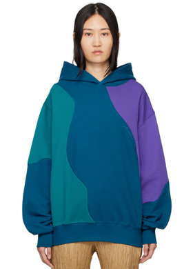 A woman wearing a colorful blue, purple and green Andersson Bell hoodie