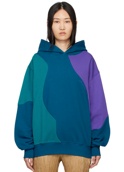 A woman wearing a colorful blue, purple and green Andersson Bell hoodie