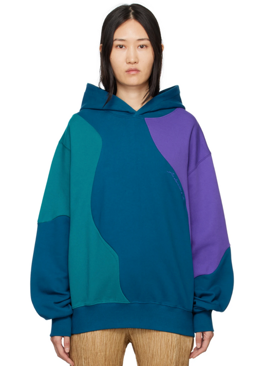 A woman wearing a colorful blue, purple and green Andersson Bell hoodie