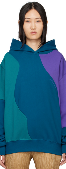 A woman wearing a colorful blue, purple and green Andersson Bell hoodie