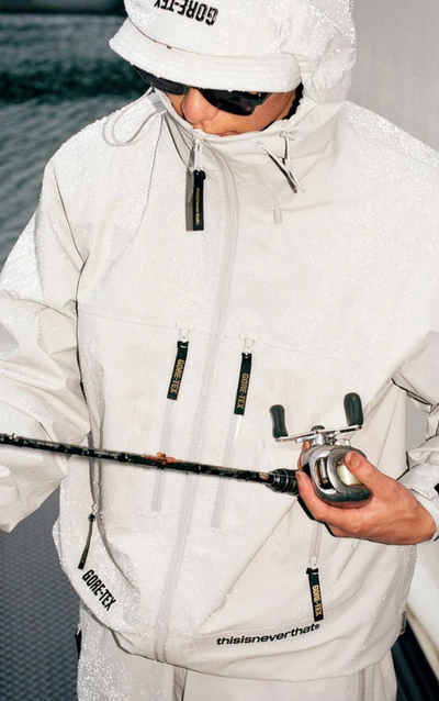 A man wearing a white technical jacket with hood on by thisisneverthat
