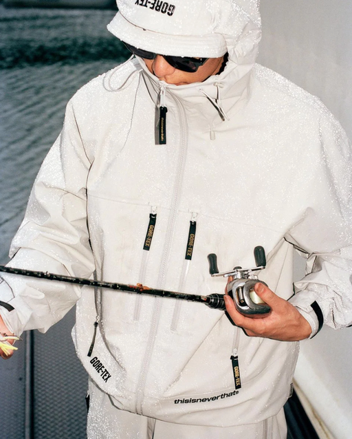 A man wearing a white technical jacket with hood on by thisisneverthat