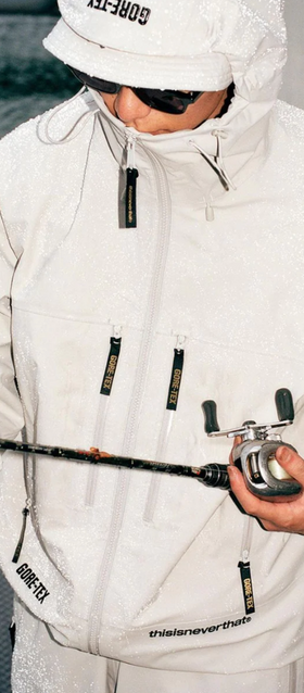 A man wearing a white technical jacket with hood on by thisisneverthat