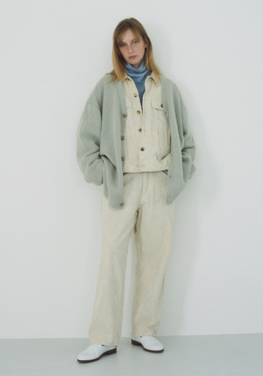 A woman wearing a light blue cardigan by URU along with cream button up with matching pants