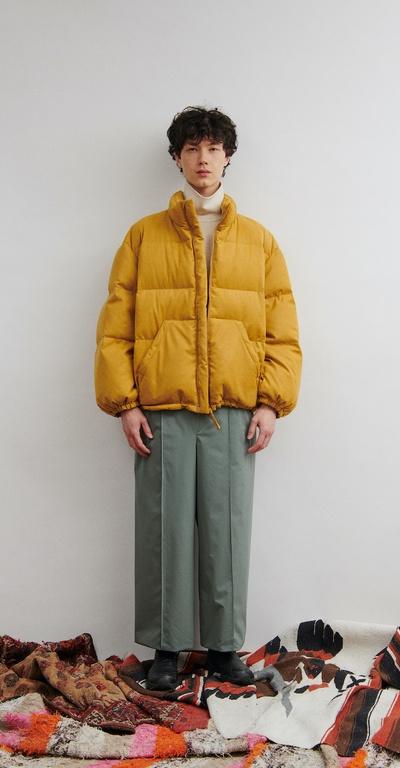 A man wearing a clean orange DIGAWEL puffy jacket with oversize slacks