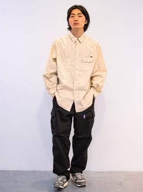 A man wearing an oversize TNF Purple Label with button up cream and black pants