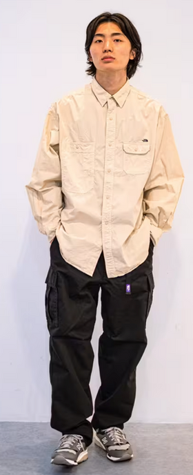 A man wearing an oversize TNF Purple Label with button up cream and black pants