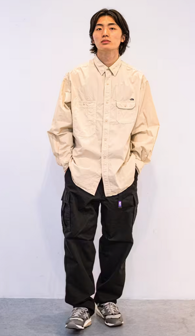 A man wearing an oversize TNF Purple Label with button up cream and black pants
