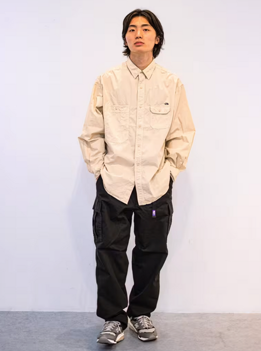 A man wearing an oversize TNF Purple Label with button up cream and black pants