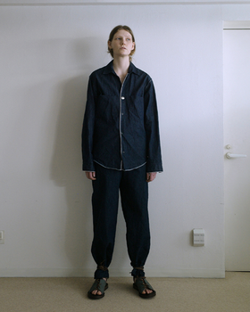 A person wearing a zip up black jacket and matching pants by SUNSEA
