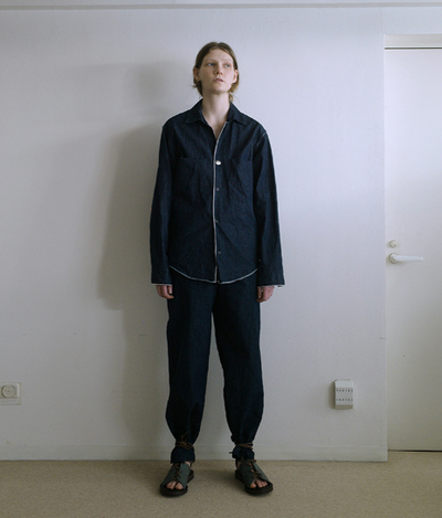 A person wearing a zip up black jacket and matching pants by SUNSEA