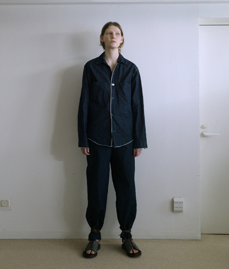 A person wearing a zip up black jacket and matching pants by SUNSEA