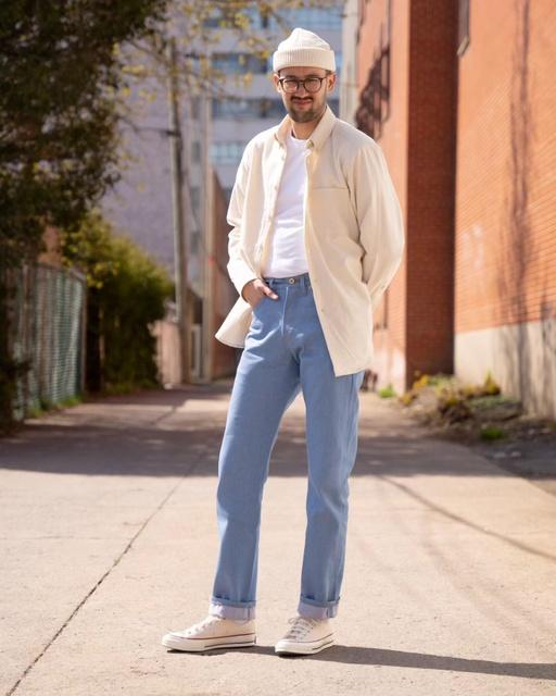 A man wearing Naked & Famous blue jeans and cream button up