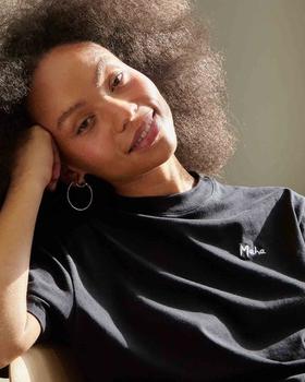 A woman wearing a black Maha logo t-shirt
