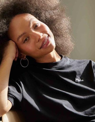 A woman wearing a black Maha logo t-shirt