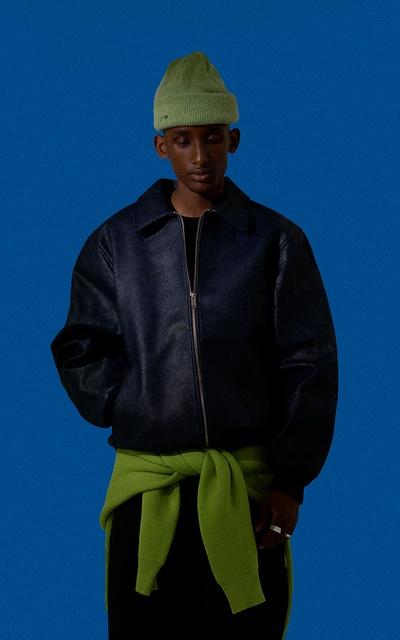 A man wearing a dark Arte Antwerp jacket with a green beanie and matching green sweater