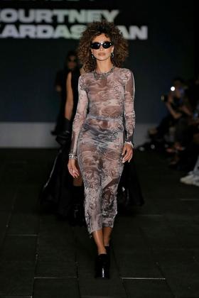 A woman walking the runway in a boohoo outfit and sunglasses