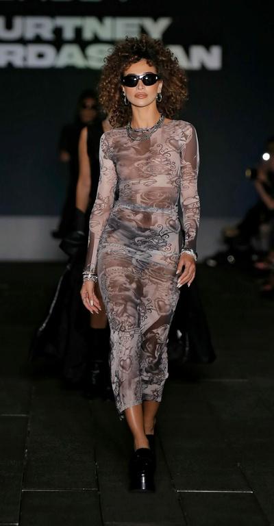A woman walking the runway in a boohoo outfit and sunglasses