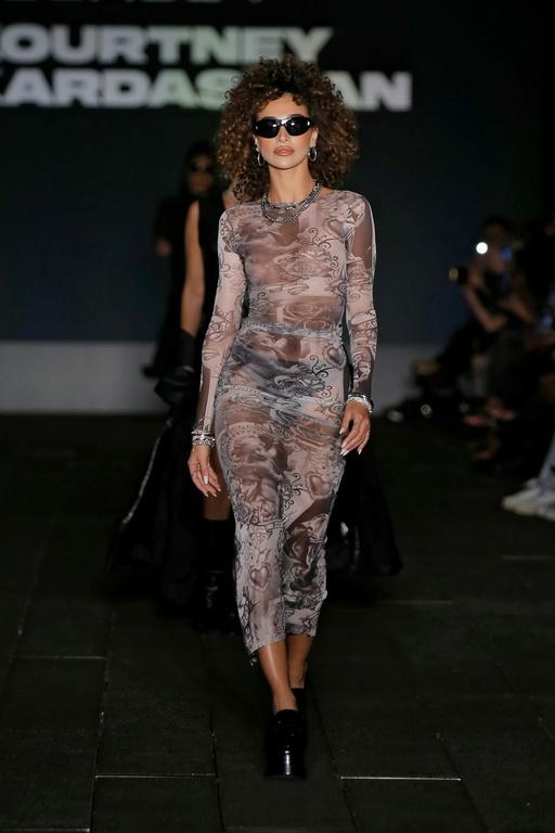 A woman walking the runway in a boohoo outfit and sunglasses