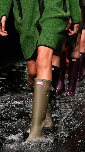 A woman walking the runway wearing a pair of green Hunter Boots