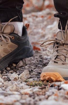 A man wearing a pair of brown and orange Oboz trail shoes