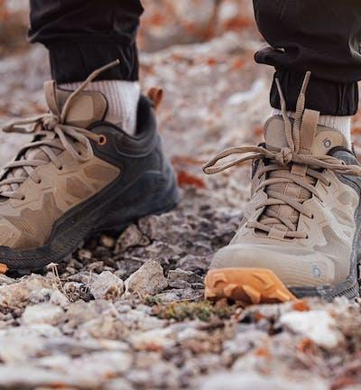 A man wearing a pair of brown and orange Oboz trail shoes