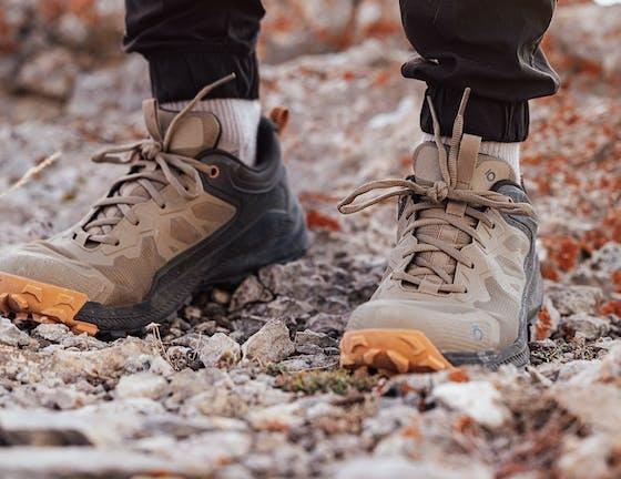 A man wearing a pair of brown and orange Oboz trail shoes