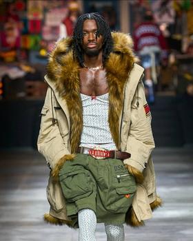 A man walking the runway wearing a Dsquared2 outfit with green shorts
