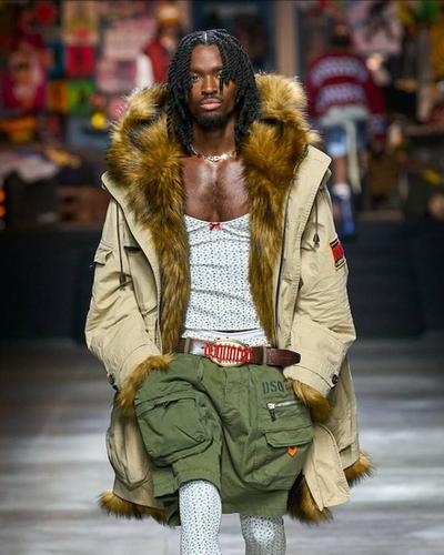A man walking the runway wearing a Dsquared2 outfit with green shorts