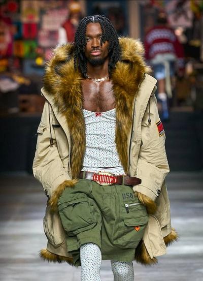 A man walking the runway wearing a Dsquared2 outfit with green shorts