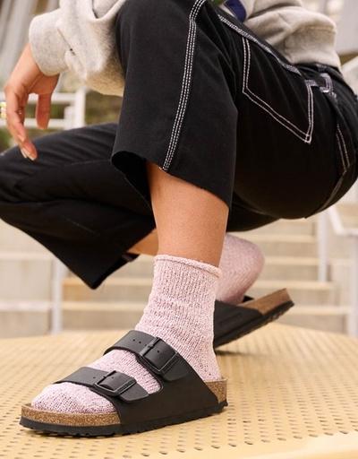 A woman wearing a brown classic Birkenstocks with pink socks