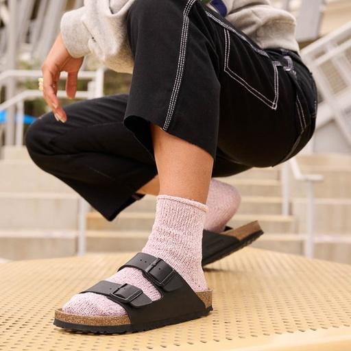 A woman wearing a brown classic Birkenstocks with pink socks