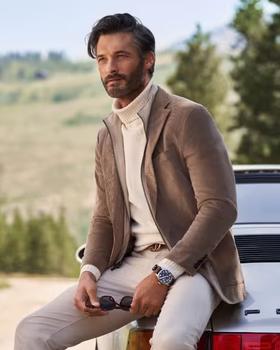 A man wearing a brown suit jacket and turtleneck