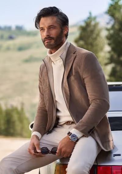 A man wearing a brown suit jacket and turtleneck