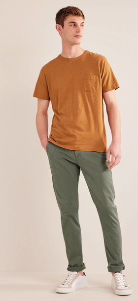 A man wearing an orange boden t-shirt with green pants