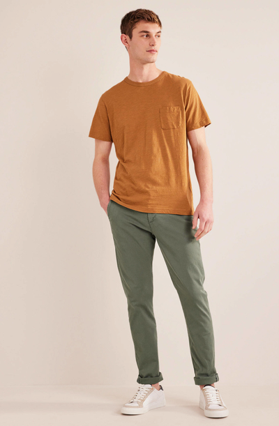 A man wearing an orange boden t-shirt with green pants