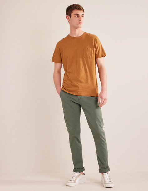A man wearing an orange boden t-shirt with green pants