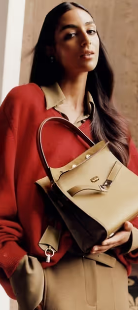 A woman wearing a Tony Burch red sweater with a brown purse