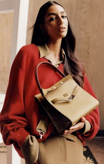 A woman wearing a Tony Burch red sweater with a brown purse